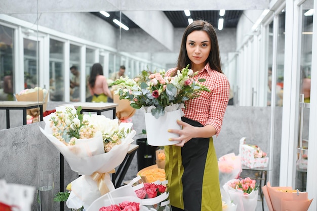 Mooie bloemist bij bloemenwinkel Vrouw die werkt in bloemenwinkel met kopie ruimte Succesvolle bloemist lachend