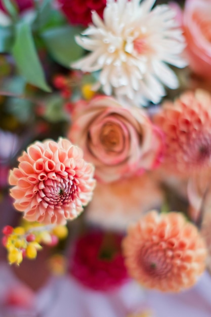 Mooie bloemsamenstelling met herfstoranje en rode bloemen en bessen Herfstboeket in vintage vaas op een houten tafel met roze tissue