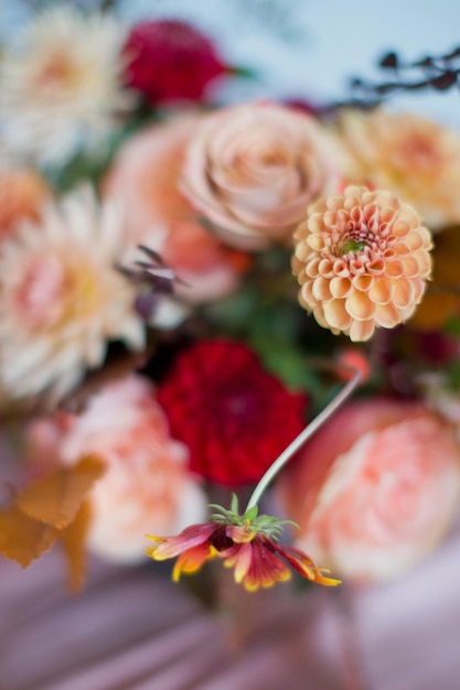Mooie bloemsamenstelling met herfstoranje en rode bloemen en bessen Herfstboeket in vintage vaas op een houten tafel met roze tissue