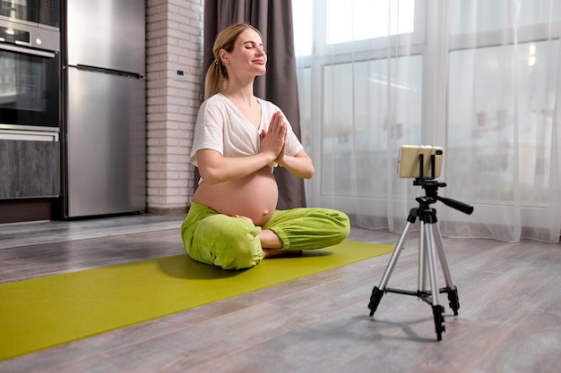 Mooie blonde blanke zwangere vrouw doet yoga-oefeningen online video kijken