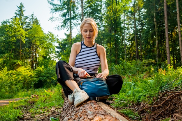 Mooie blonde haar vrouw zit op log in forest