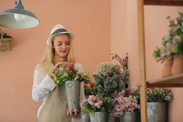 Mooie blonde haren meisje staan met vertrouwen voor bloem in open verkoopt flora winkel.