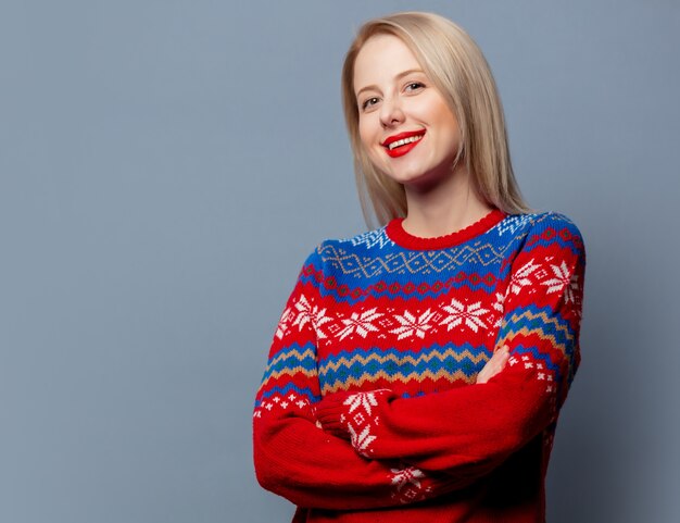 Mooie blonde in kerstmissweater op grijs