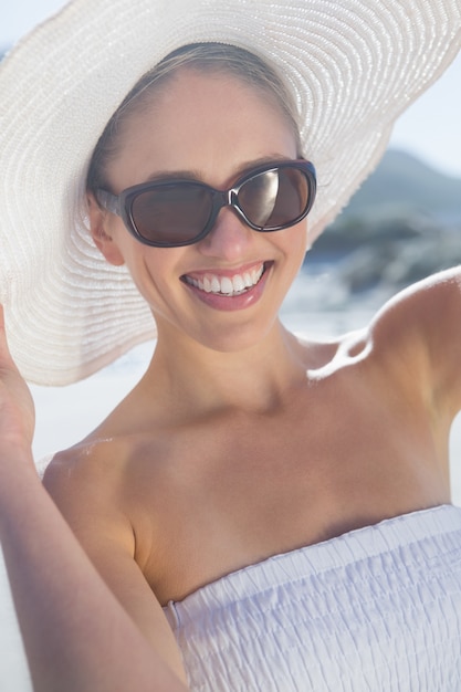 Mooie blonde in witte jurk en sunhat op het strand