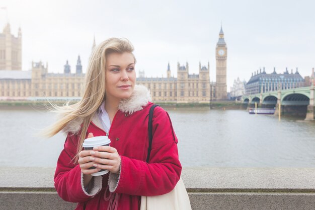 Mooie blonde jonge vrouw met een kopje thee in Londen