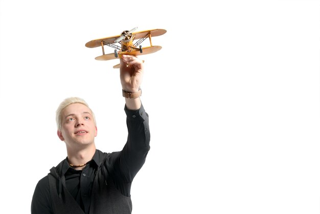 Mooie blonde man gekleed in het zwart spelen met een modelvliegtuig geïsoleerd