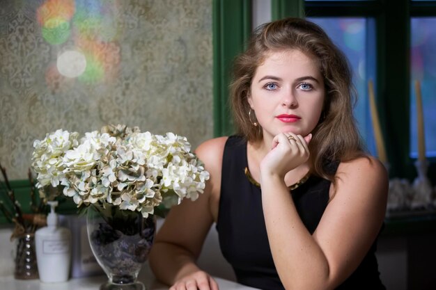 Mooie blonde meid in een café aan een tafel Jonge vrouw in een mooi restaurant kijkt naar de camera