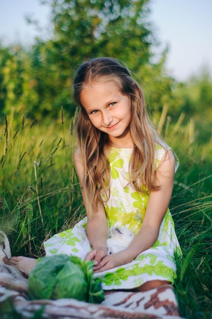 mooie blonde meisje met kleine konijnen zitten in het groene gras.