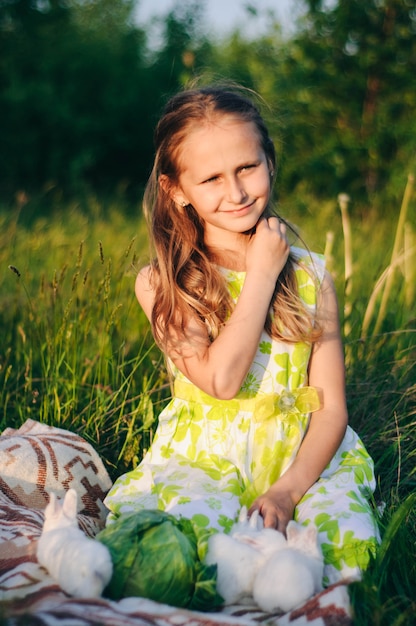 mooie blonde meisje met kleine konijnen zitten in het groene gras.