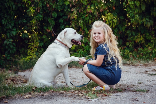 Foto mooie blonde meisje speelt met haar hond. outdoor portret. serie