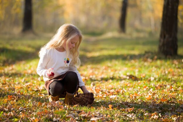 Mooie blonde meisjeskindwandelingen in het herfstpark