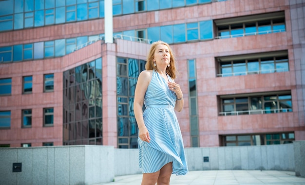 Mooie blonde poseren in een blauwe jurk op straat