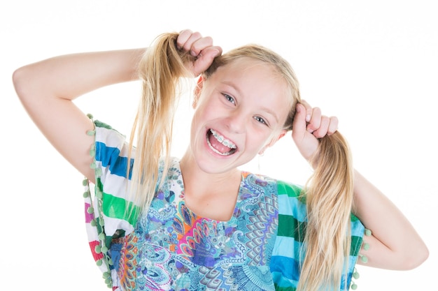 Foto mooie blonde pre-tiener die haar haar vasthoudt en glimlacht