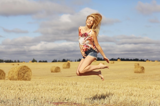 mooie blonde springt in glooiend veld zongeluk