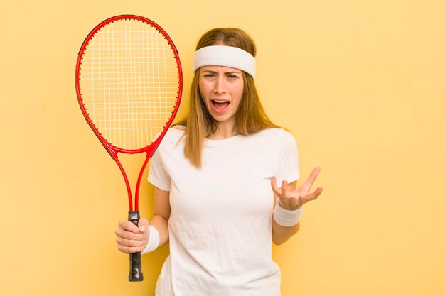 Mooie blonde vrouw die boos, geïrriteerd en gefrustreerd tennisconcept kijkt