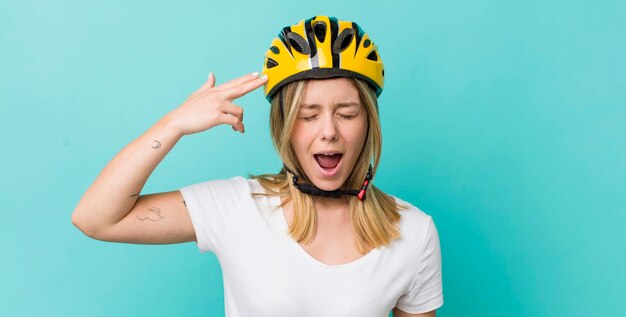 Mooie blonde vrouw die ongelukkig en gestrest zelfmoordgebaar kijkt en een pistoolteken fietsconcept maakt