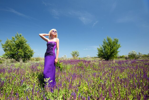 Mooie blonde vrouw die paarse bloemen plukt