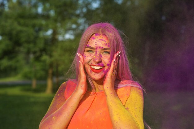 Mooie blonde vrouw die plezier heeft met kleurrijke droge verf in het park. Concept voor festival Holi