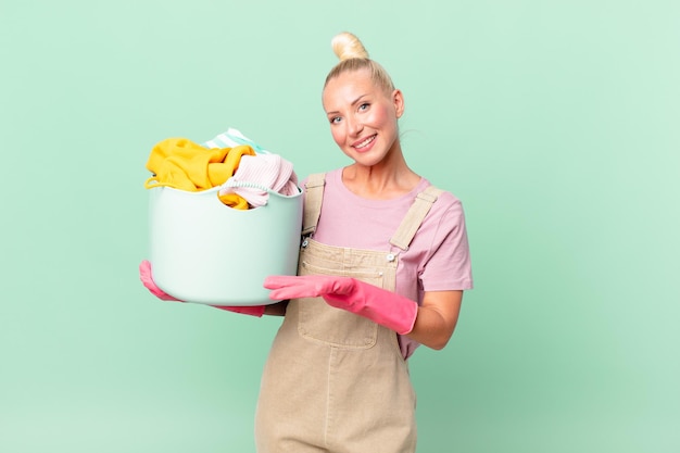 Mooie blonde vrouw die vrolijk lacht, zich gelukkig voelt en een concept voor het wassen van kleding toont