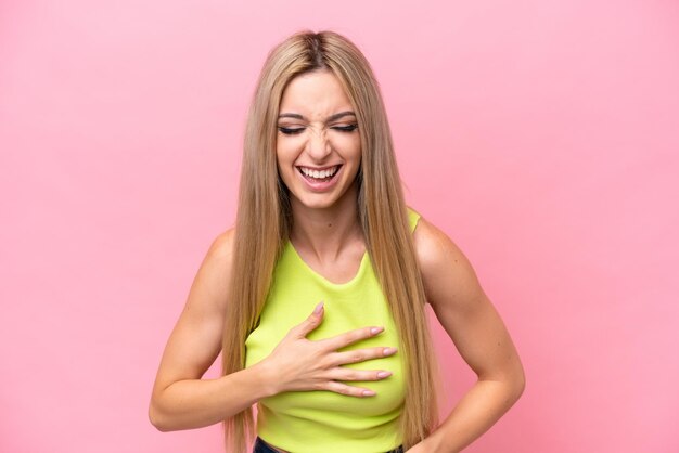 Mooie blonde vrouw geïsoleerd op roze achtergrond veel glimlachend