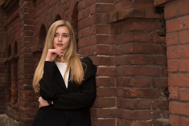 Mooie blonde vrouw gekleed in casual stijl bij bakstenen muur