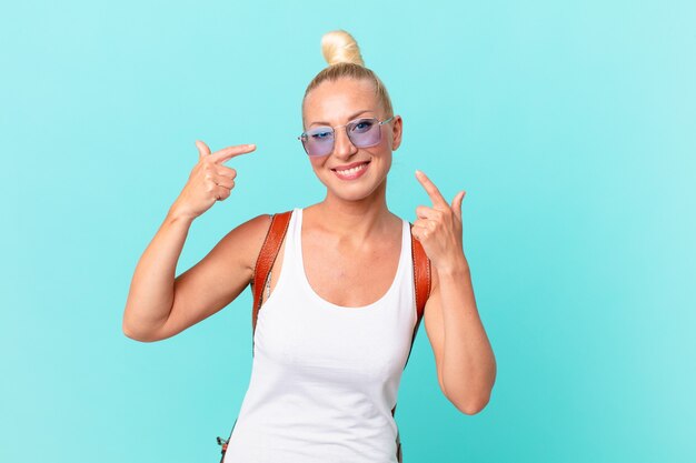 Mooie blonde vrouw glimlachend vol vertrouwen wijzend naar eigen brede glimlach. zomer concept