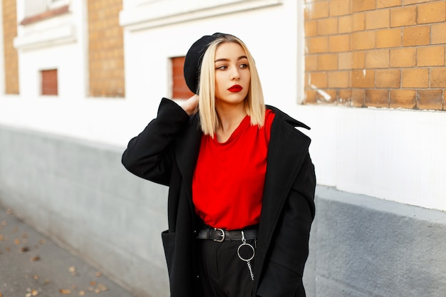 Mooie blonde vrouw met een baret in modieuze herfstkleren die zich voordeed op straat