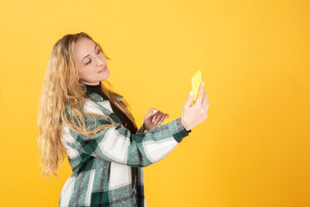 Mooie blonde vrouw met gele tinten van de mobiele telefoon