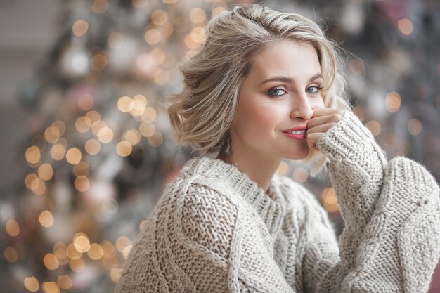 Mooie blonde vrouw met kerstboom. Portret van aantrekkelijke vrouw close-up.