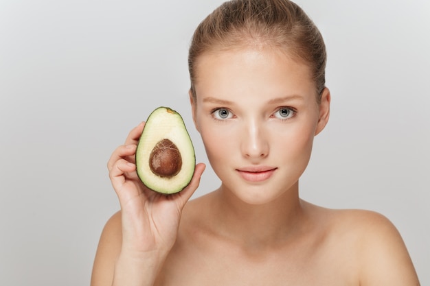 Mooie blonde vrouw met perfecte huid en een avocado