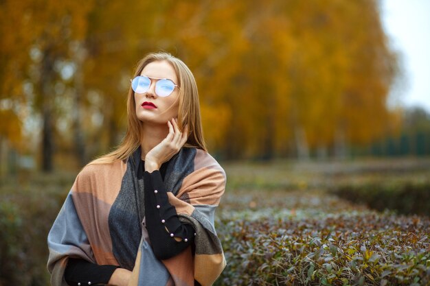 Mooie blonde vrouw met rode lippen trui, sjaal en bril dragen. Ruimte voor tekst