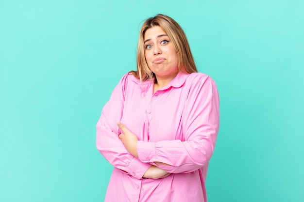 mooie blonde vrouw met rondingen die haar schouders ophaalt, zich verward en onzeker voelt