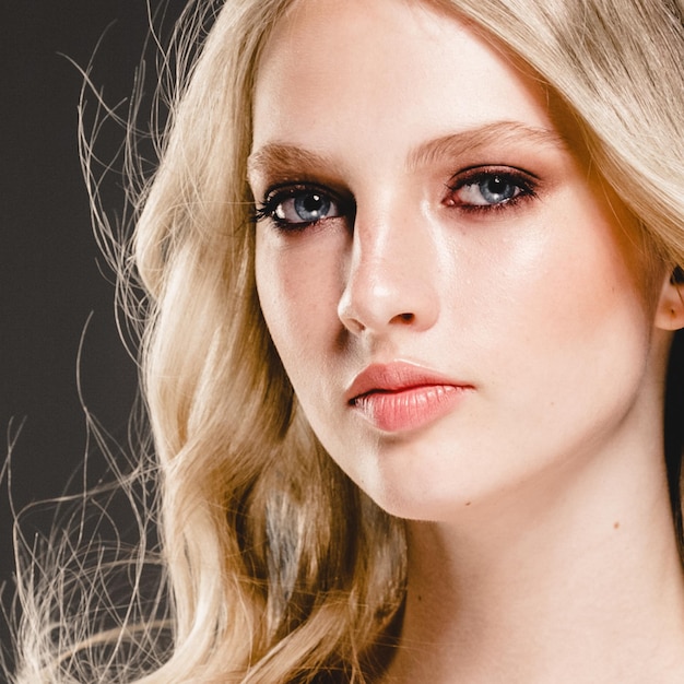 Mooie blonde vrouw schoonheid model meisje met perfecte make-up en kapsel op zwarte achtergrond.