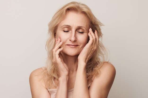 Mooie blonde vrouw van middelbare leeftijd lachend gezicht op zoek camera portret Elegante rijpe dame geen make-up 50 jaar oude close-up geïsoleerd op wit