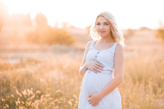 Mooie blonde zwangere vrouw in zonlicht