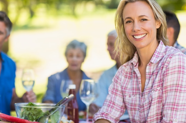 Mooie blondevrouw die bij camera tijdens een picknick glimlachen