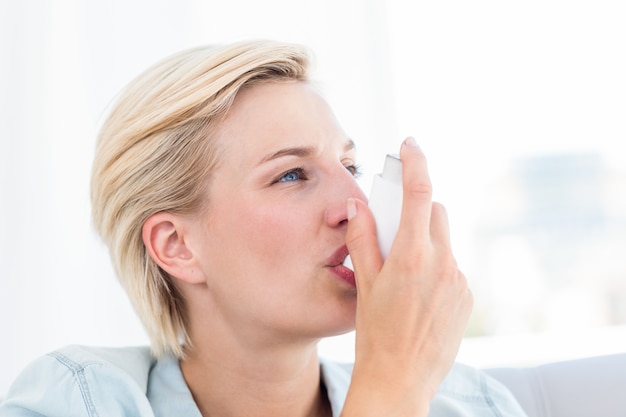 Mooie blondevrouw die haar inhaleertoestel gebruiken