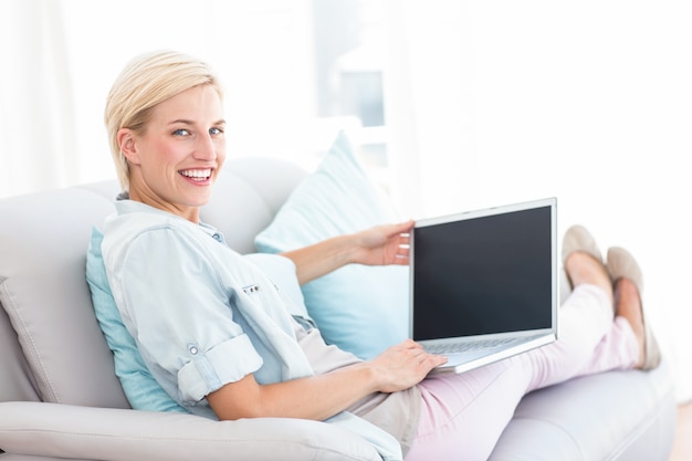 Mooie blondevrouw die haar laptop met behulp van