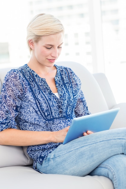 Mooie blondevrouw die haar tablet op de laag gebruiken