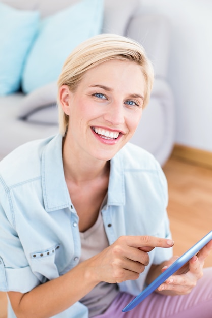 Mooie blondevrouw die haar tablet op de vloer gebruiken