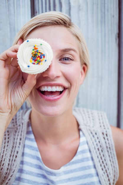 Mooie blondevrouw die met cupcake grimassen trekken