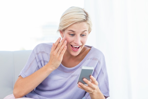 Mooie blondevrouw die met haar mobiele telefoon texting