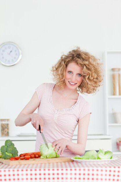 Foto mooie blondevrouw die sommige groenten in de keuken koken