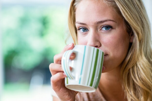 Mooie blondevrouw het drinken thee in de keuken