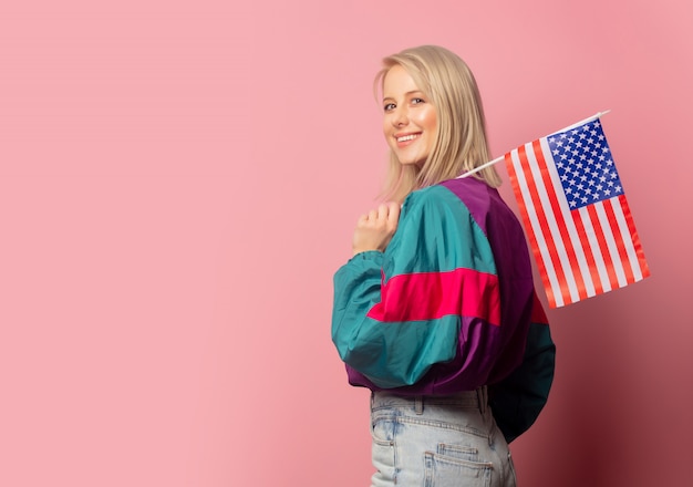 Mooie blondevrouw in jaren 90kleren met de vlag van de VS
