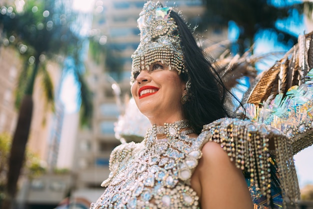 Mooie Braziliaanse vrouw die een kleurrijk carnavalskostuum draagt en glimlacht tijdens de straatparade van Carnaval in de stad.