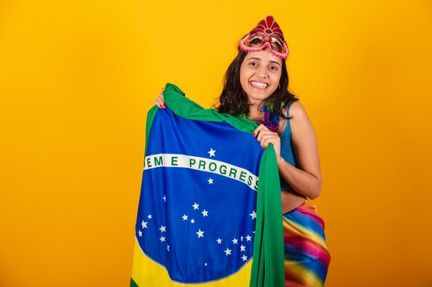 Mooie braziliaanse vrouw in carnaval-kleding met vlag van brazilië