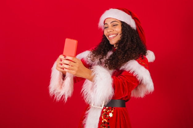 Mooie braziliaanse zwarte vrouw verkleed als kerstkleren van de kerstman die zelfportret maken met smartphone