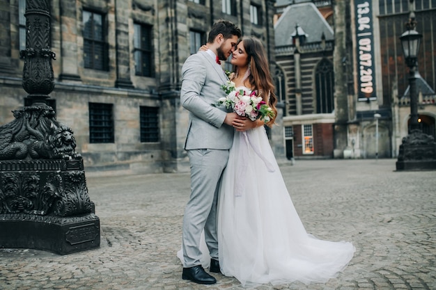 Mooie bruid en bruidegom die en op hun huwelijksdag in openlucht omhelzen kussen