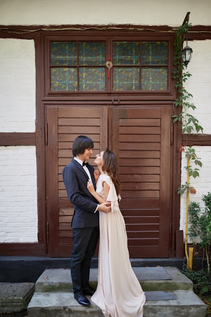 Mooie bruid en bruidegom staan dicht bij elkaar op oud huis achtergrond, trouwfoto, mooi paar, trouwdag, portret.